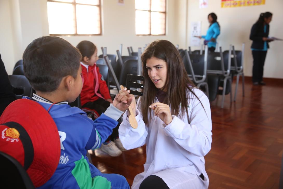 Medical volunteer performs a simple eye test for a young boy in Peru. Projects Abroad volunteer explains an eye test to a local boy during her spring break in Peru.